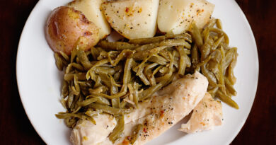 Baked green bean, chicken, and potato casserole topped with melted cheese in a white dish